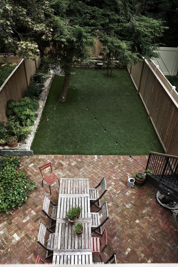 an overhead view of a small backyard with lawn and patio furniture, including table and chairs