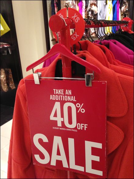 a red sale sign hanging on a clothes rack