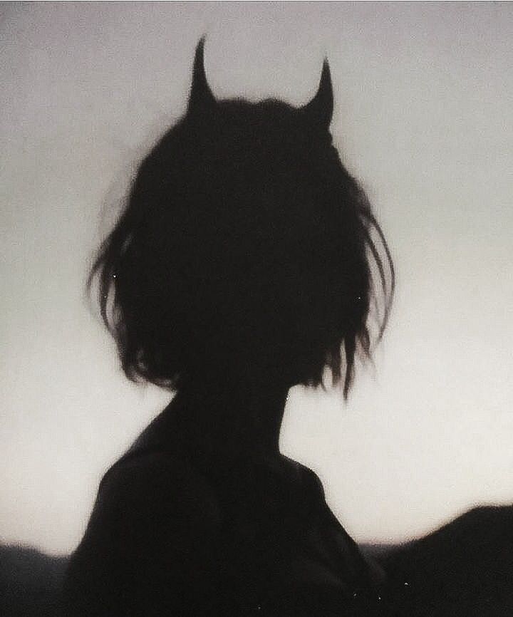 the silhouette of a woman with horns on her head and hair blowing in the wind