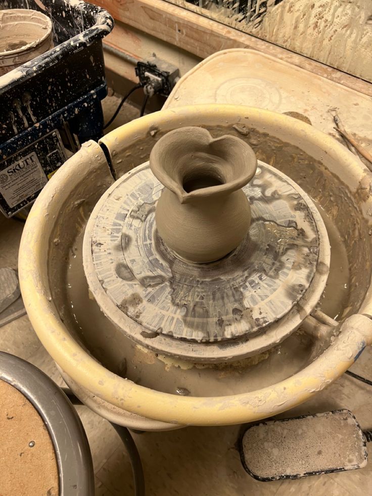 an unfired heart shaped vase made from clay sitting on a potter’s wheel. Wheel Thrown Pottery Forms, Potter Aesthetic Clay, Ceramic Vase Wheel Thrown, Ceramics Class Aesthetic, Wheel Projects Pottery, Pottery Asthetic Ideas, Simple Wheel Thrown Pottery, Ceramics Wheel Thrown, Ceramics Wheel Ideas