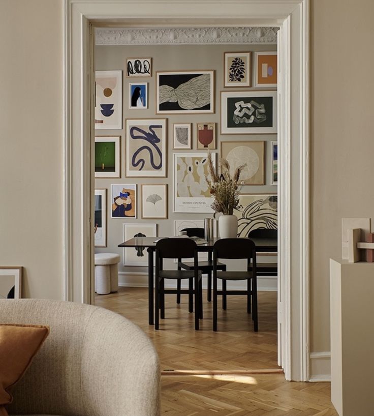 a living room filled with furniture and pictures on the wall next to a dining table