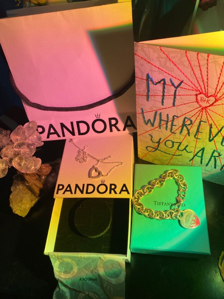 several cards and jewelry are on display in front of a bag that says, my pandora wherever you land