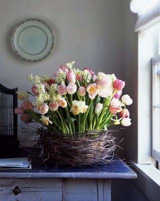 a basket filled with flowers sitting on top of a blue table next to a window