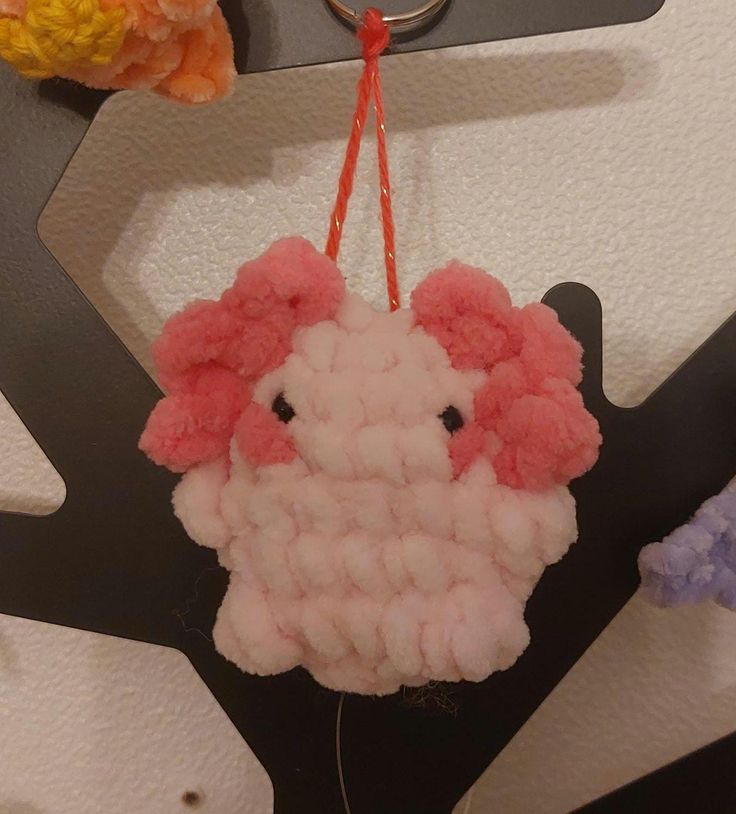 an ornament made to look like a sheep is hanging from a hook on a wall