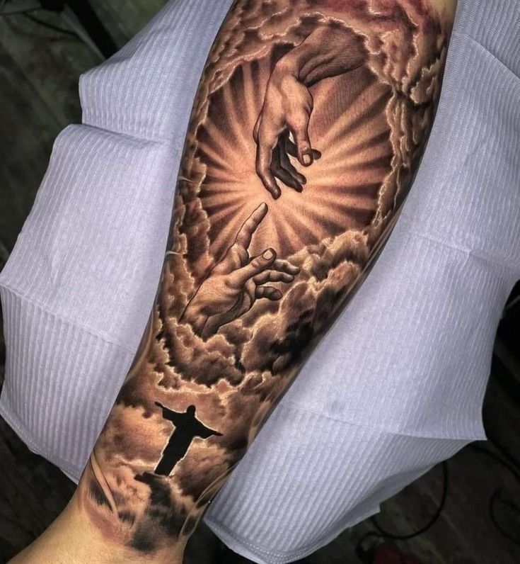 a man's arm with a cross and jesus on it, in the clouds