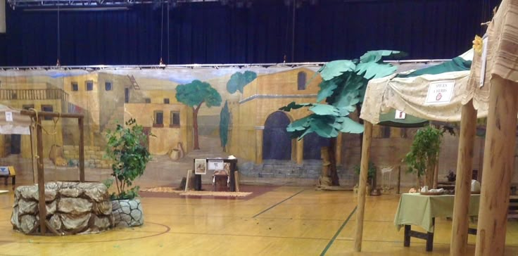 an indoor stage set up for a performance with palm trees in the center and painted murals on the walls