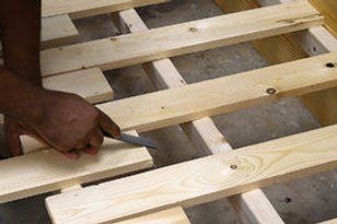 a person cutting wood with a pair of scissors on top of the wooden planks