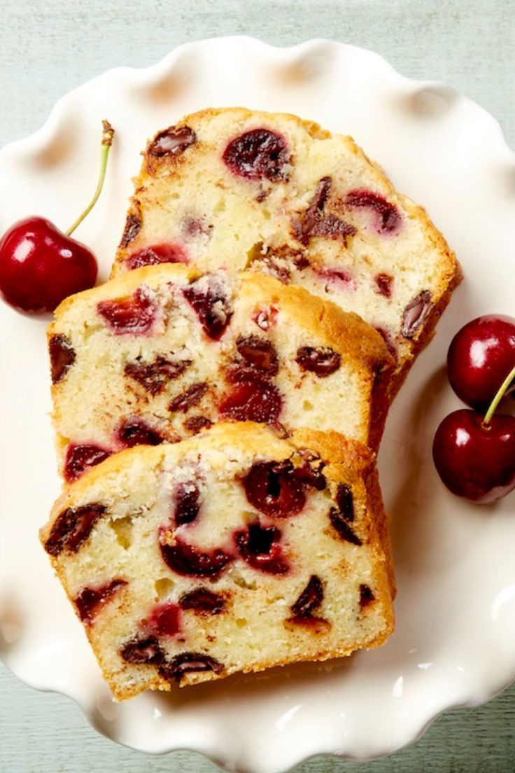 two slices of cherry bread on a plate with cherries next to it and one slice cut in half