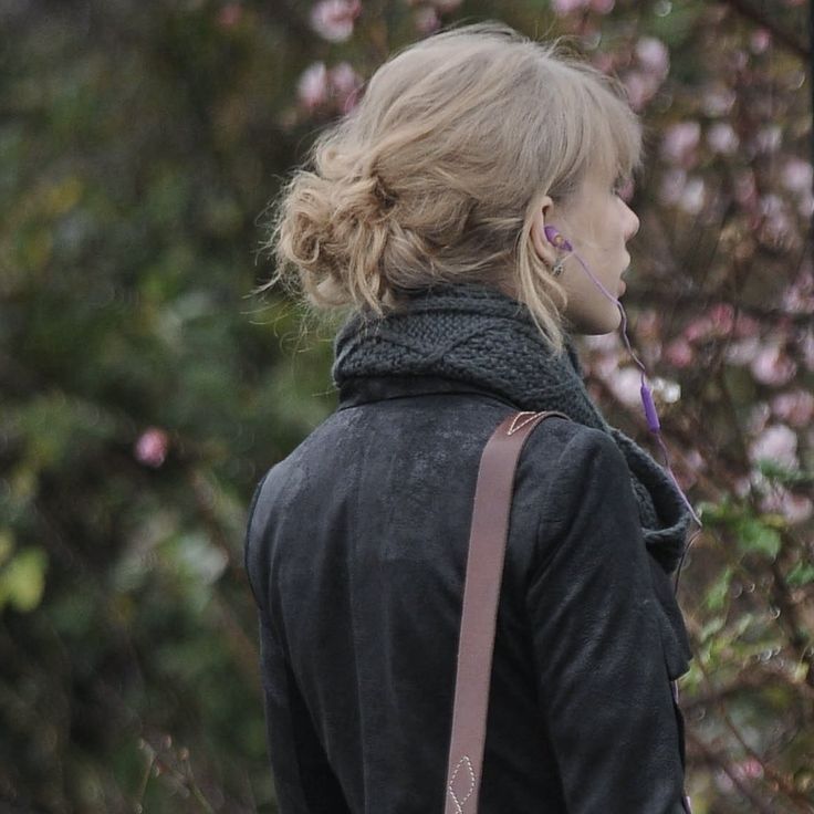 a woman with her back to the camera, wearing a black jacket and carrying a brown bag