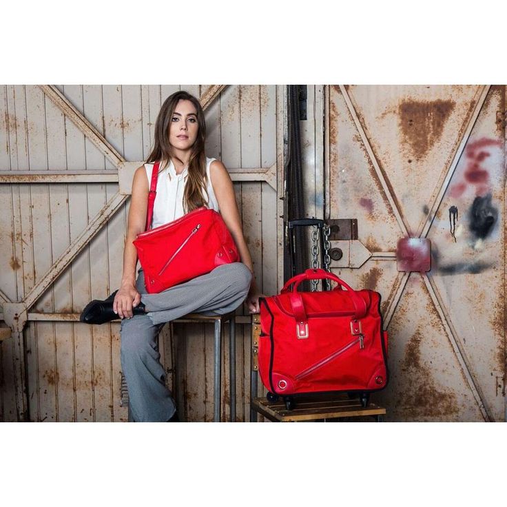 a woman sitting on a chair holding two red bags