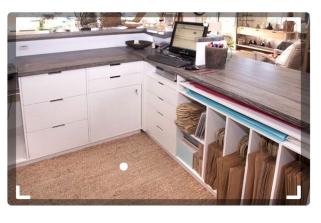 a laptop computer sitting on top of a wooden table in a kitchen next to white cabinets