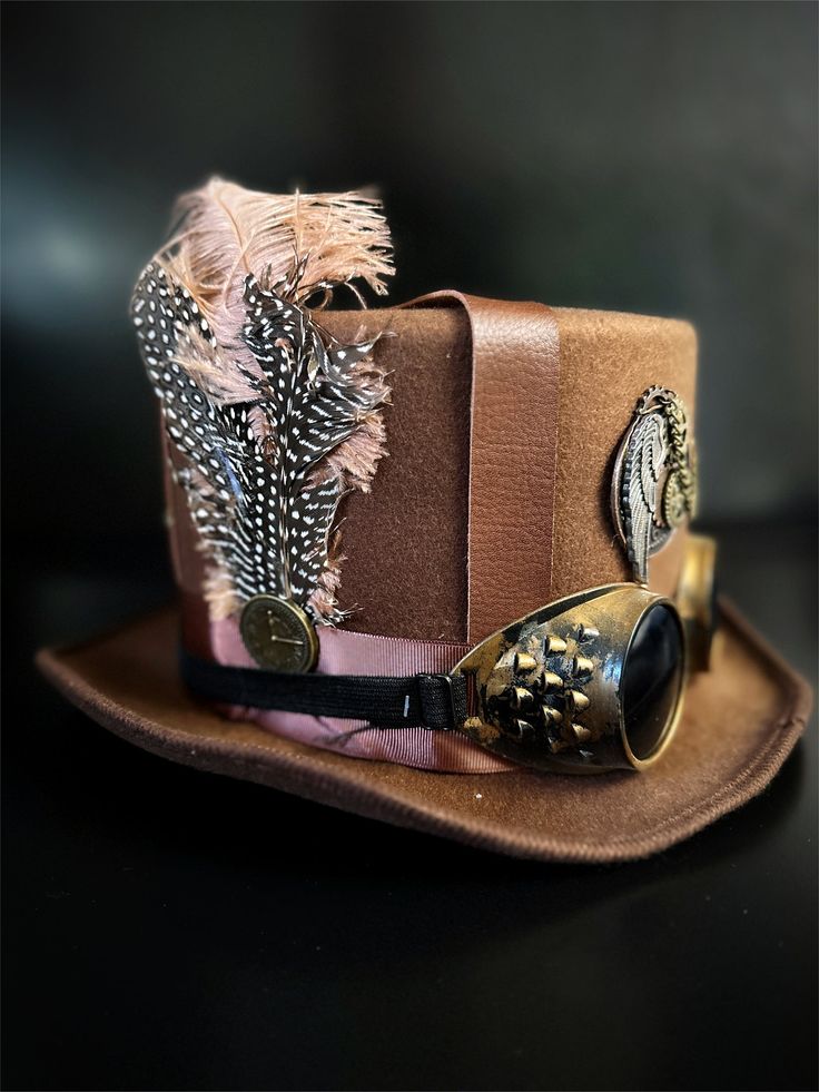 Our brown steampunk hat with goggles and feathers radiates sophistication, join the steampunk revolution and claim your spot among the fashion-forward. Perfect for themed events, cosplay, or adding a dash of steampunk to your everyday attire.


Age Group/Gender - Adult/Unisex

Size/Type - One size fits all adults
Color - Brown Steampunk Top Hat With High Crown For Themed Events, Steampunk Hat For Themed Events, Vintage Hat Costume Accessories For Cosplay, Vintage Hat For Cosplay, Vintage Fitted Top Hat For Cosplay, Steampunk Brimmed Costume Accessories For Party, Steampunk Costume Accessories With Brimmed Shape, Steampunk Brimmed Costume Accessories For Costume Party, Steampunk High Crown Hat For Themed Events