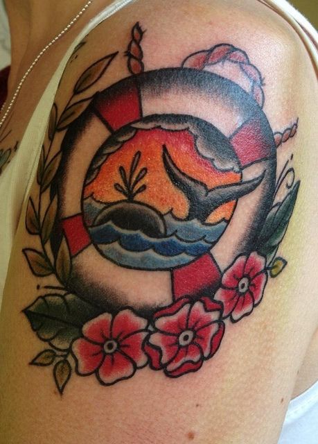 a woman's arm with a dolphin and flowers tattoo on her left upper arm