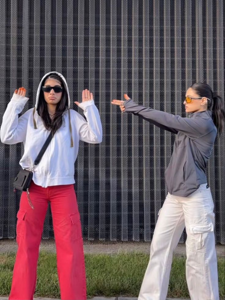 two women standing next to each other with their arms in the air and one holding her hands out