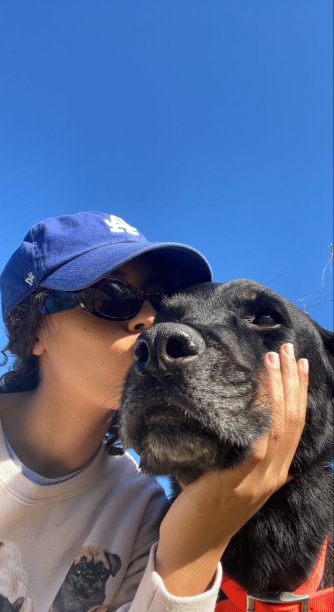 a person kissing a dog on the nose with a blue sky in the back ground