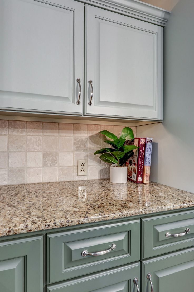 This refresh took some of the kitchen's already nice features (the layout, backsplash, countertops) and updated it to make the client's style even better. 
All cabinet doors, including the cabinetry around the island was all updated. They ended up going with the green for the lower cabinets and the island. For the upper cabinets, they chose a very subtle and lighter shade of green; still drawing in colors from the countertop and tying in the dark green from the lower cabinets. White Countertop Green Cabinets, Sage Countertop Kitchen, Light Green Kitchen Cabinets Brown Counter, Green Cabinets With Silver Hardware, Painted Cabinets Granite Countertops, Kitchen Design Brown Countertop, How To Make Front Of House Look Better, Green Cabinets Tan Countertops, Green Kitchen With Brown Countertops