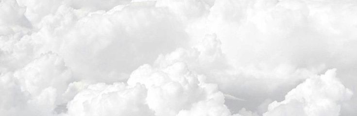 a man riding skis down the side of a snow covered slope in front of clouds