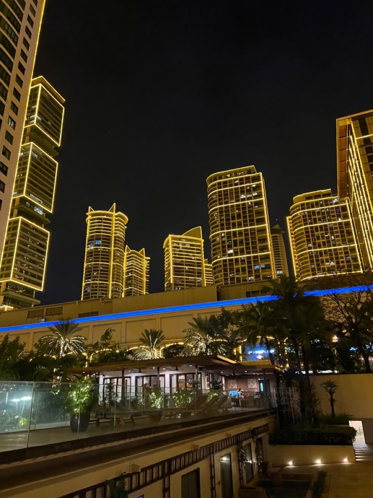 the city skyline is lit up at night with skyscrapers in the background and lights on