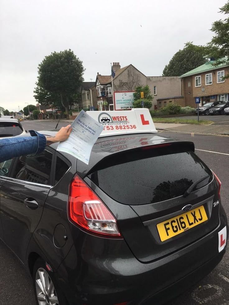 a person holding up a parking ticket in the back of a car on a city street