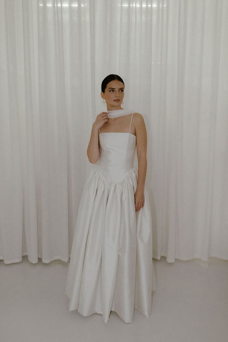 a woman standing in front of a white curtain