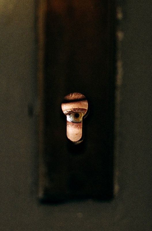 an eye is seen through the hole in a wall