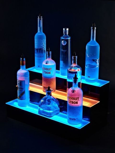 several bottles are lined up on a shelf with light coming from the top and bottom