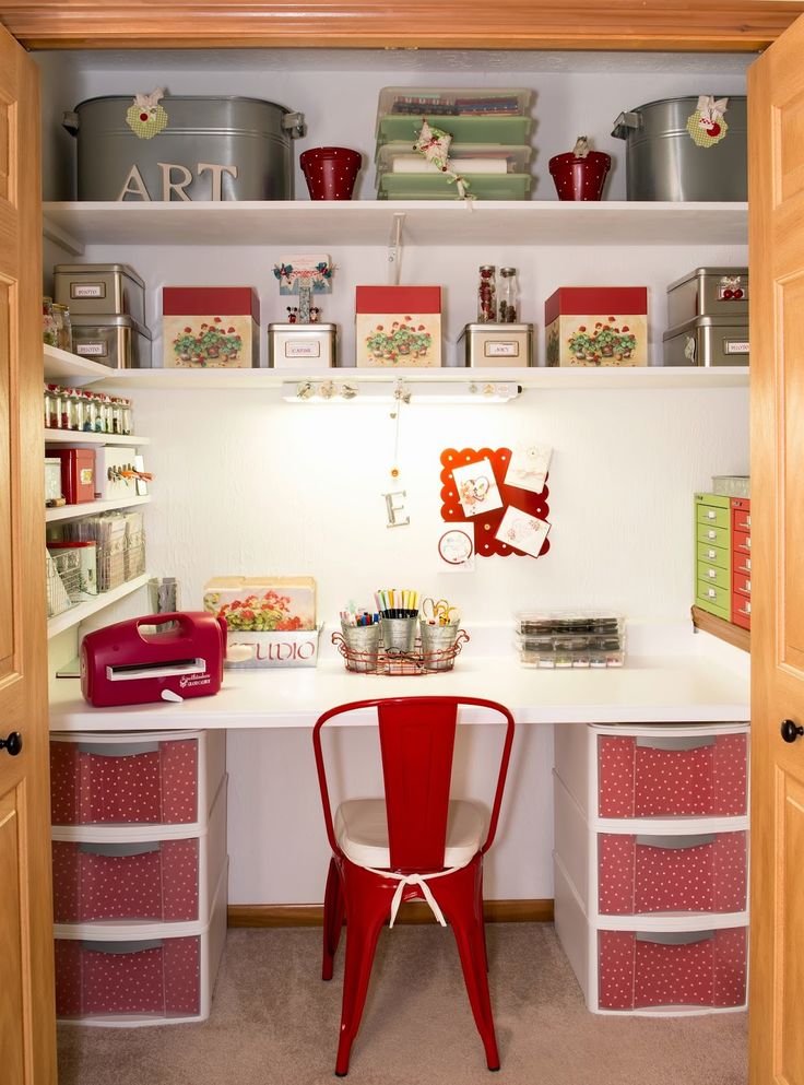 a red chair sitting in front of a white desk with lots of drawers on it