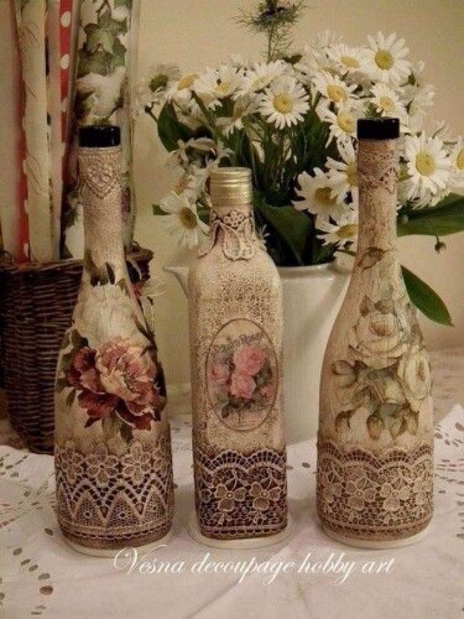 three bottles with lace and flowers on them are sitting next to a vase filled with daisies