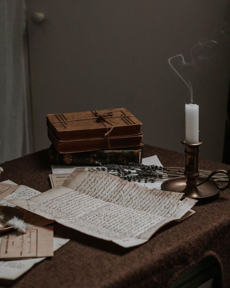 a table topped with books and candles next to a candle holder on top of a table