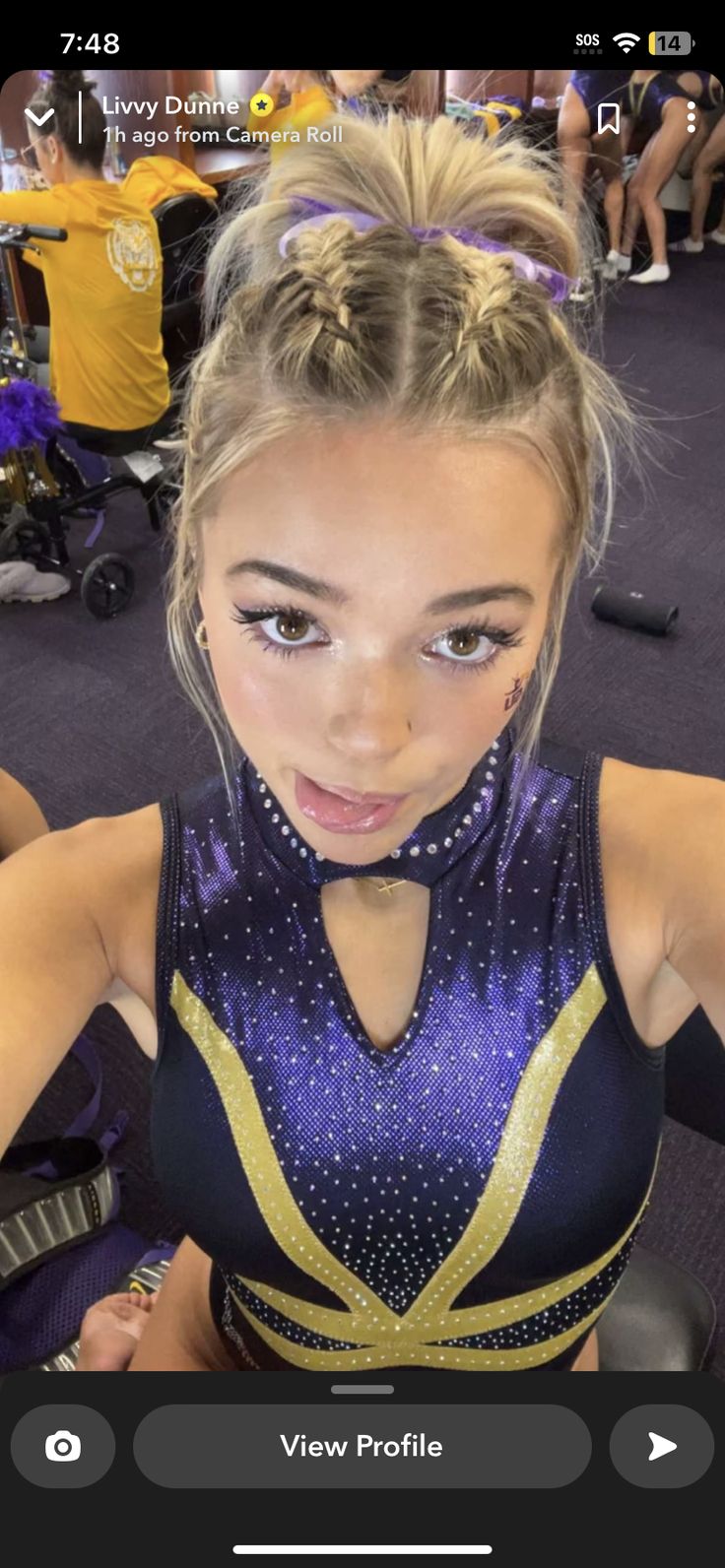 a woman with blonde hair wearing a purple and gold cheerleader outfit posing for the camera