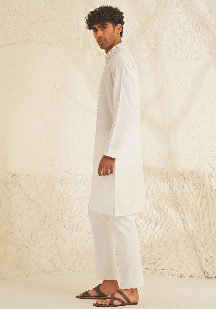 Presenting an exquisite Porcelain White Silk Kurta Set, featuring a sophisticated Chinese collar, elegant metallic silver buttons, and intricate hand-embroidered detailing on the neckline and sleeves. Paired with trendy white pants, this ensemble is perfect for engagements, Roka ceremonies, or puja events, combining timeless elegance with contemporary style. Composition : Dupion Silk Care: Dry Clean Only and Vacuum Storage This product can be customized for sleeves, length and colour Delivery : 4-6 weeks as the product is hand crafted. Check Size Guide or choose MySize for free customisation (All Sizes above XL can be made at 15% additional cost) For more information and sizes please contact fabiliciousfashion@gmail.com or visit our Copenhagen studio. About the Designer : Shreyansh, a dist Elegant Straight Kurta With Set-in Sleeves, Elegant Semi-formal Sets For Eid, Festive Formal Lawn Suit With Naqshi Details, Fitted Kurta With Set-in Sleeves For Festive Occasions, Elegant Off-white Straight Kurta Traditional Wear, Classic Fitted Traditional Wear For Eid, White Traditional Wear With Naqshi On Straight Kurta, Classic Unstitched Traditional Wear For Formal Occasions, Festive Kurta With Set-in Sleeves