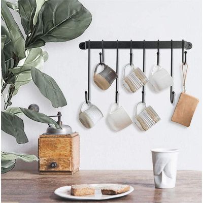 there are cups and spoons hanging on the wall next to a coffee cup holder