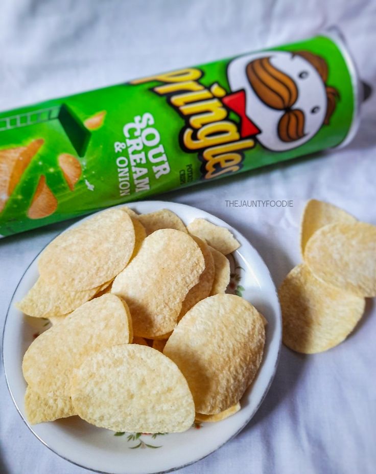 some chips are on a plate next to a can of potato chips