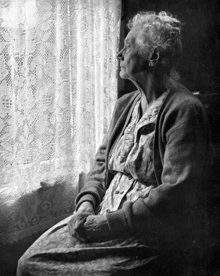 an old woman sitting in front of a window