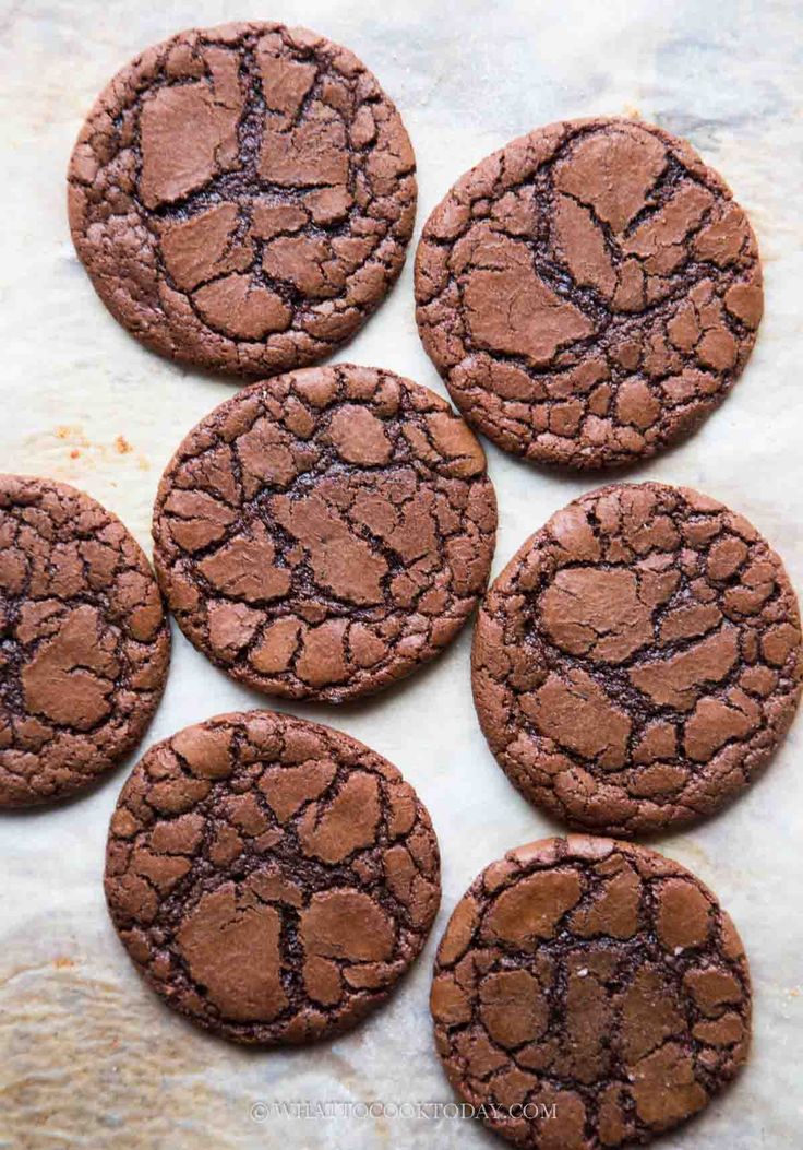 six chocolate cookies on a piece of parchment paper