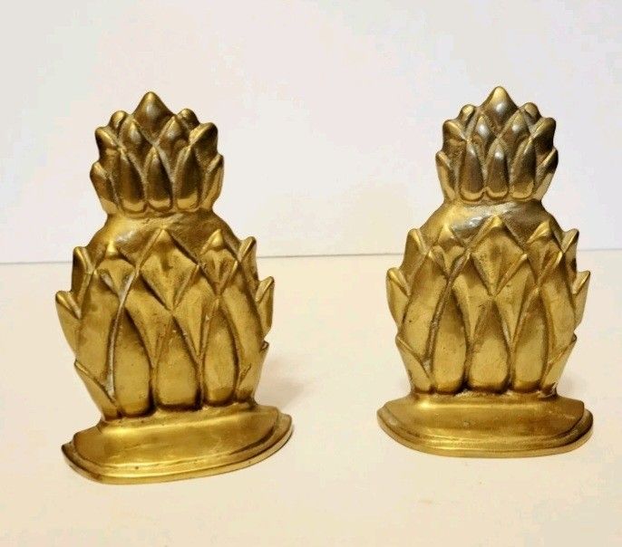 two golden pineapple shaped candlesticks sitting on a table