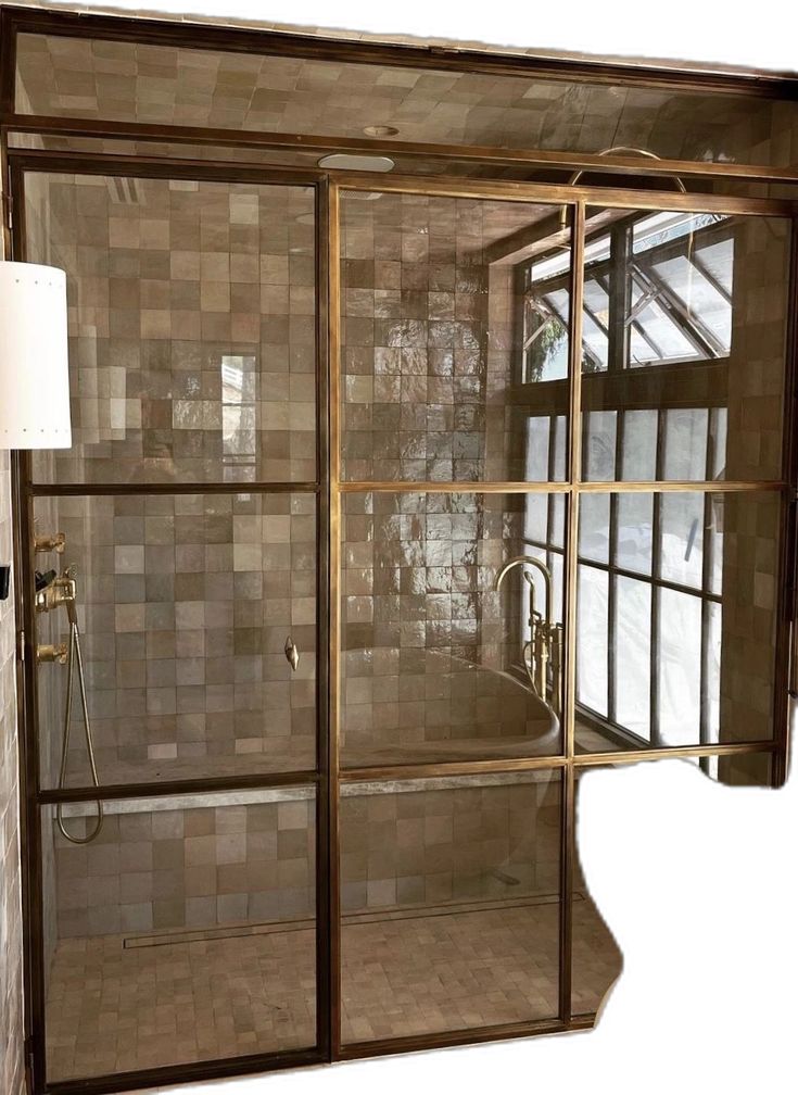 an open glass shower door in a bathroom with tile on the walls and flooring