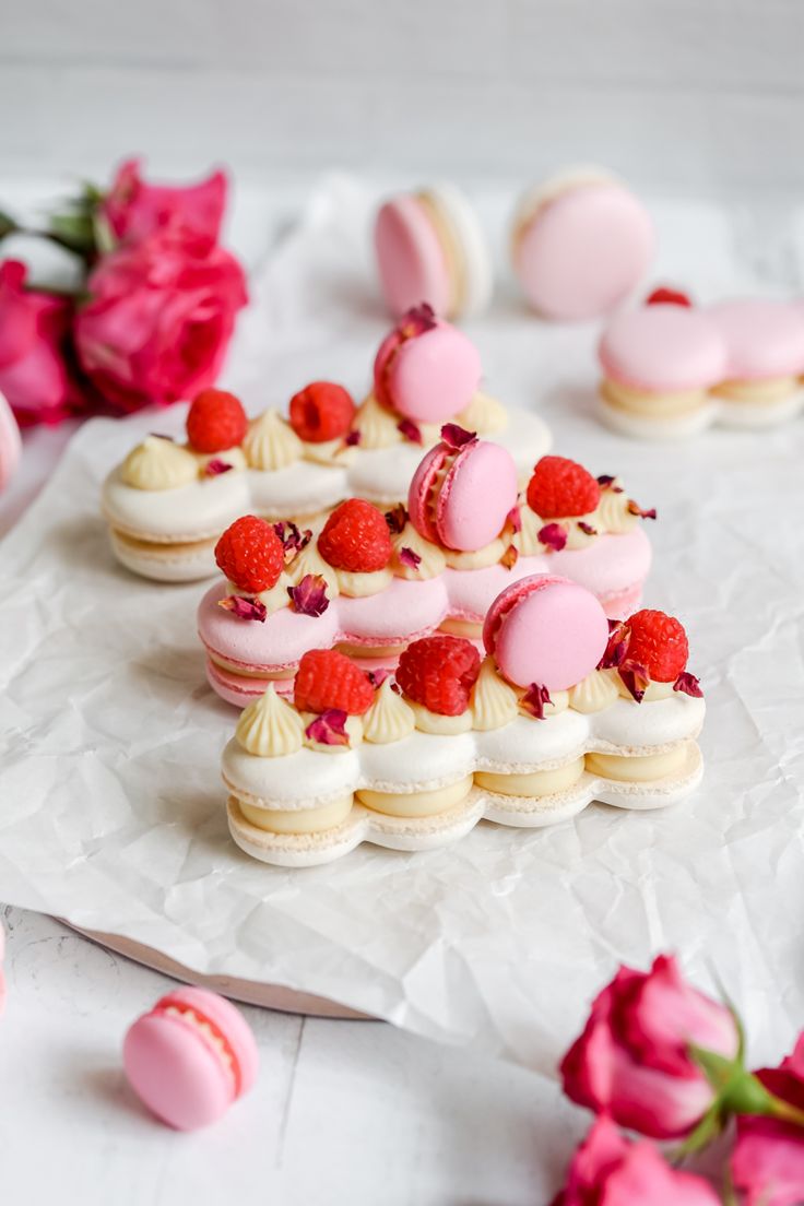 small pink and white desserts with raspberries on top, next to flowers