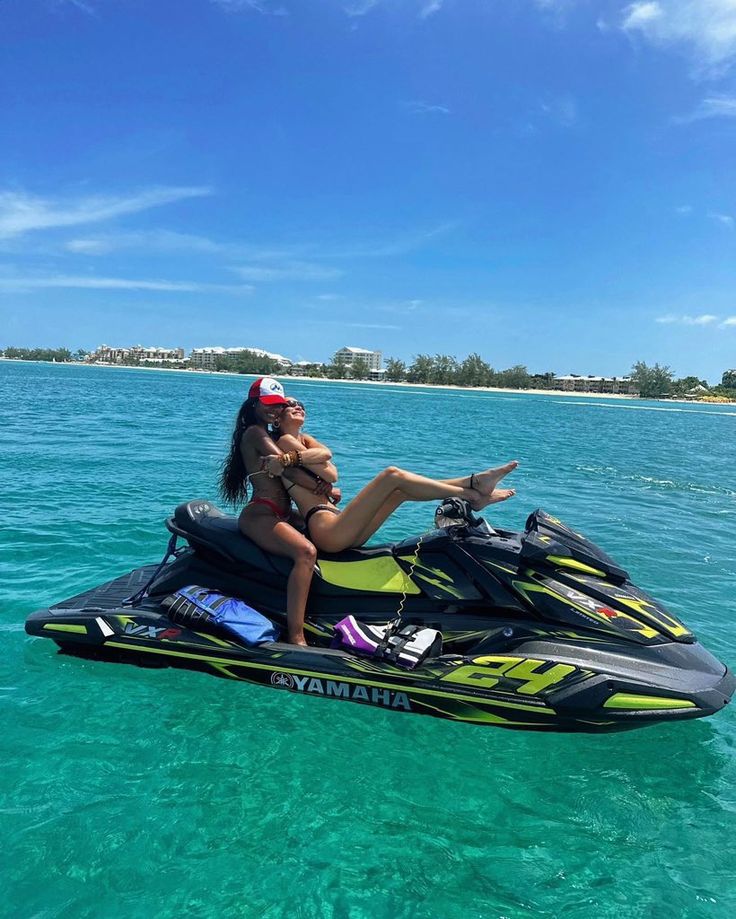 a woman riding on the back of a jet ski in clear blue water near an island