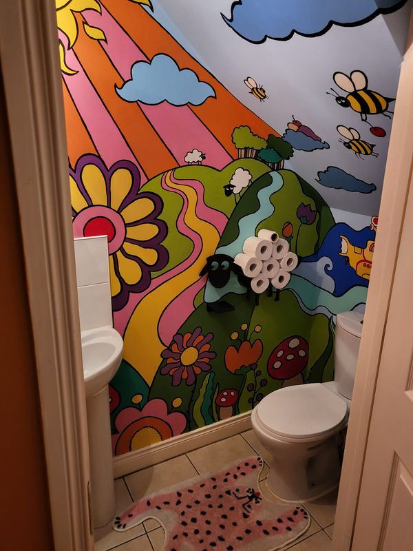 a bathroom with a colorful mural painted on the wall and toilet in the doorway area