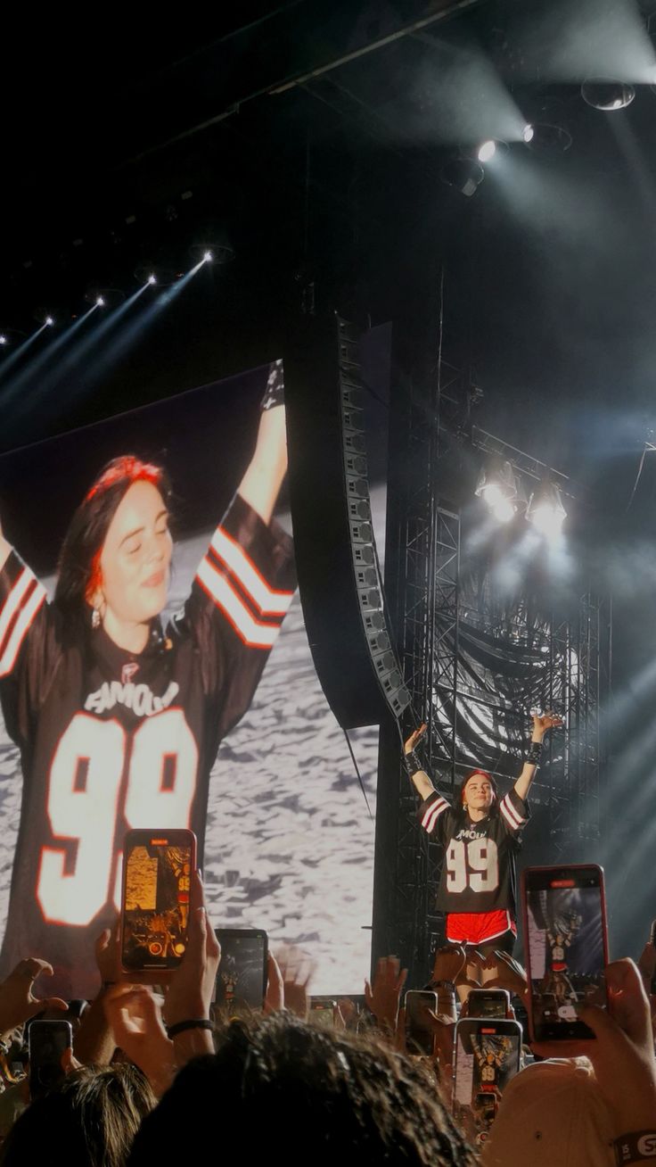 two football players on stage with their arms in the air and people holding up cell phones