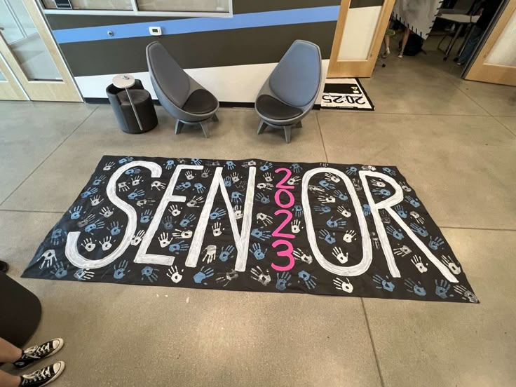 a sign that says senior on the floor in front of two chairs and a table