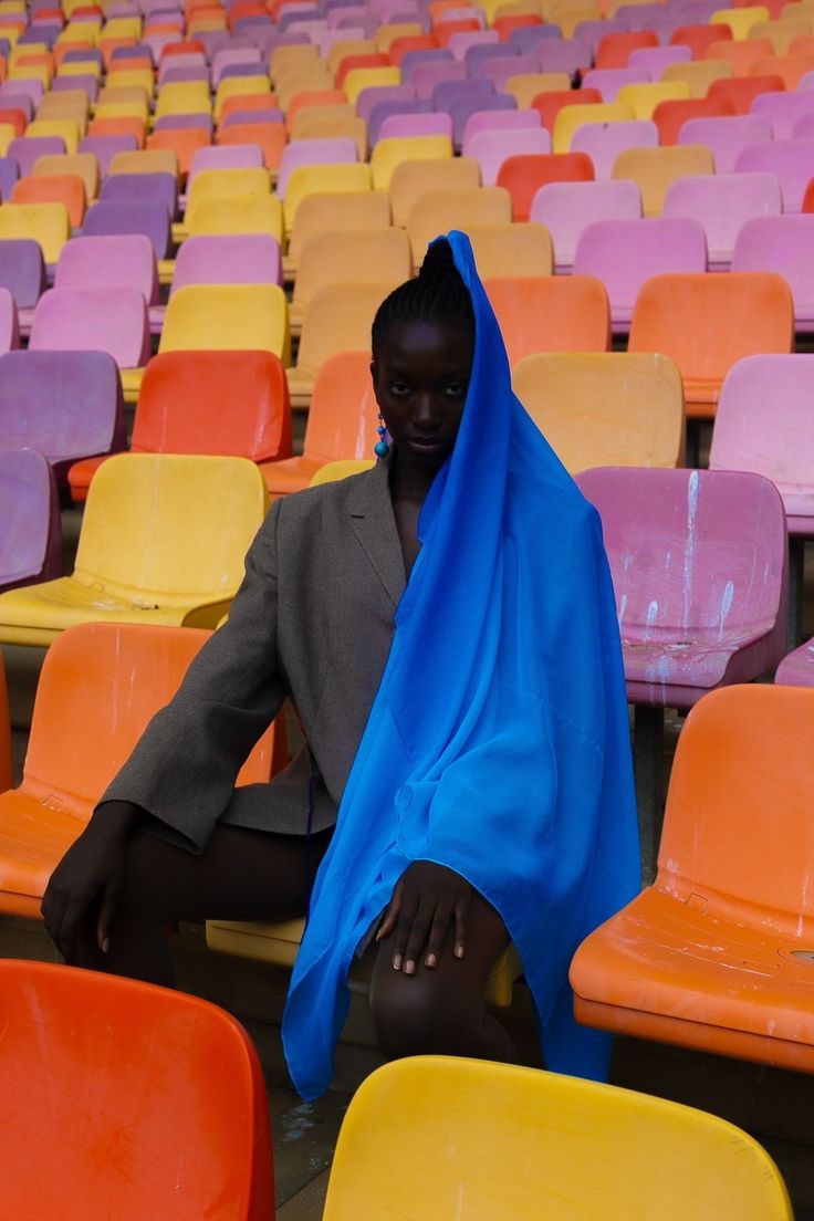 a woman sitting in an empty stadium with a blue scarf over her head and legs