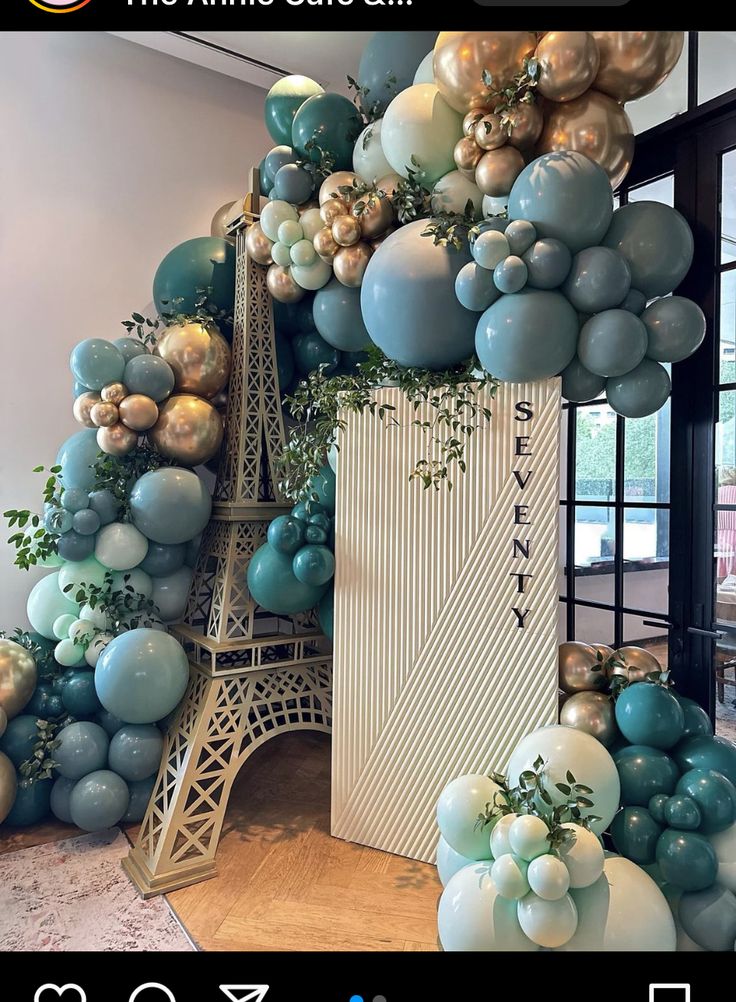 the eiffel tower is decorated with balloons and greenery in blue, gold and white