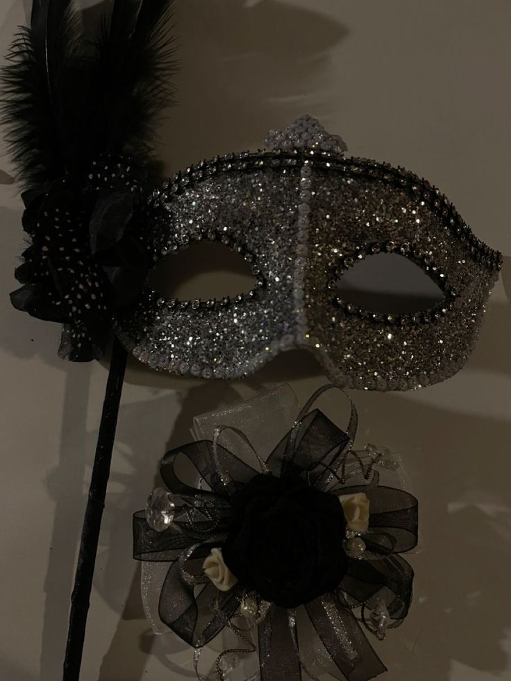 two masquerade masks are sitting on a table next to a black and white flower