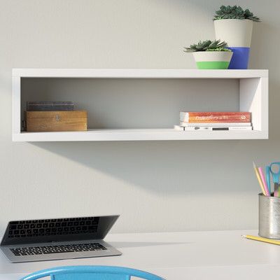 a laptop computer sitting on top of a desk next to a white shelf filled with books