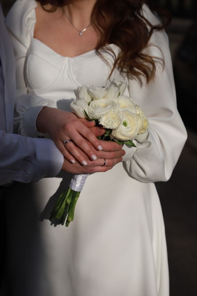 a woman in a white dress holding a bouquet of flowers next to a man in a suit