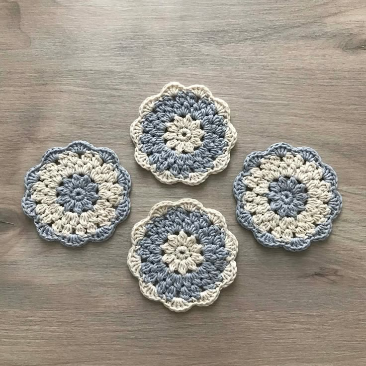 four crocheted coasters sitting on top of a wooden table