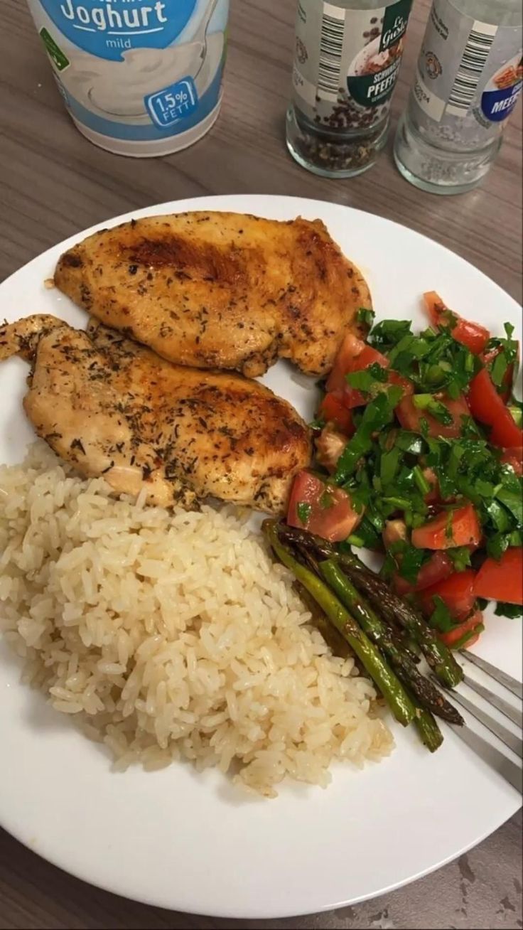 chicken, rice and asparagus on a plate with water bottles in the background