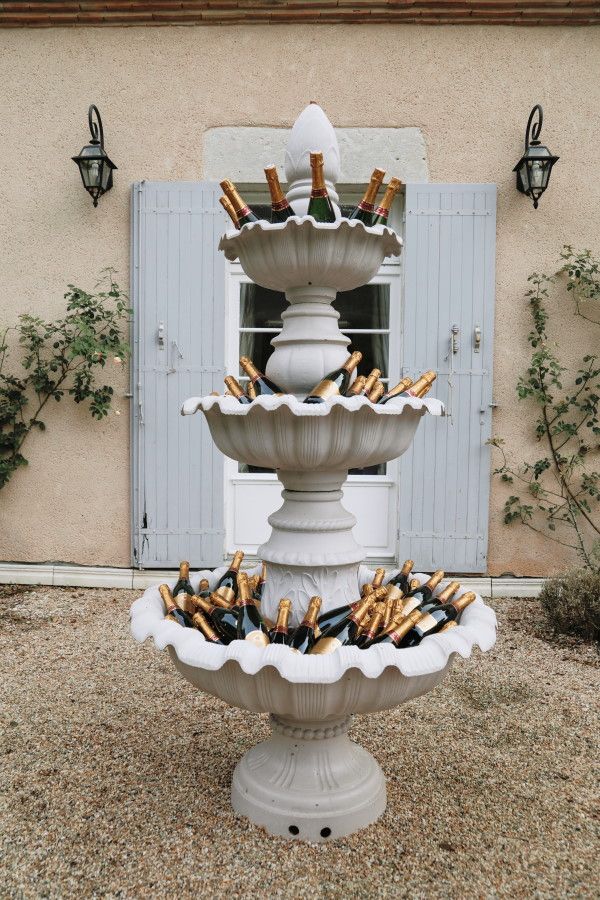 outdoor fountain filled with champagne bottles outside french chateau Champagne Holder Wedding, Fountain Centerpiece Wedding, Drink Fountain Ideas, Wine Fountain Wedding, French Event Decor, Champagne Bottle Display, After Wedding Food, French Wedding Traditions, French Engagement Party